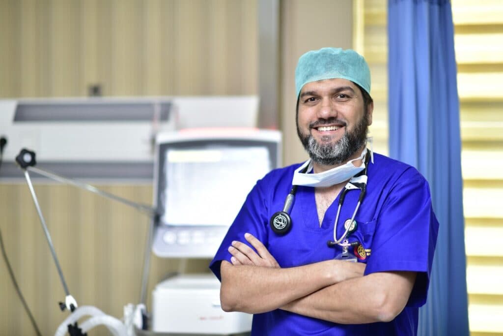 Dr. Asim Rana in scrubs and surgical cap, arms crossed in the ICU