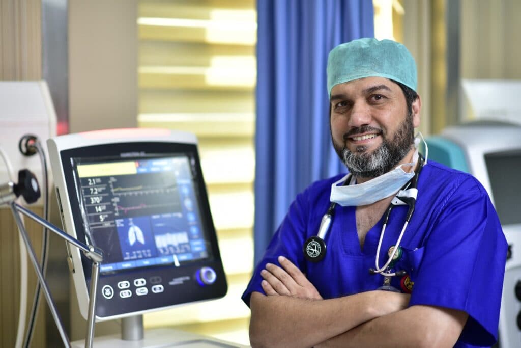 Dr. Asim Rana beside a ventilator monitor in the critical care unit